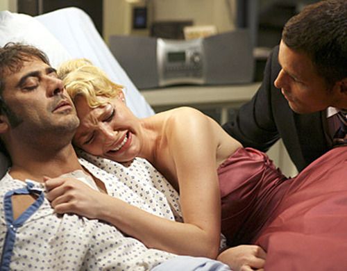 Izzie lies next to Denny's body, sobbing, while Alex goes to lift her off the bed.