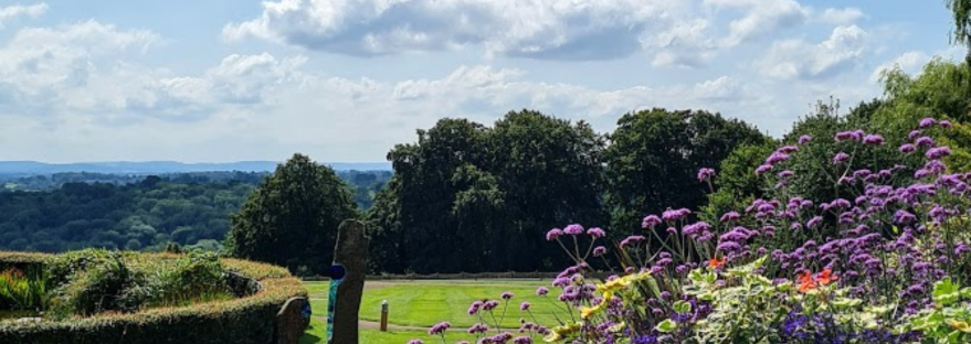 Photo of the grounds of the hospice I work at. The grass is a bright green, the sky is blue with clouds, and the sun is shining.