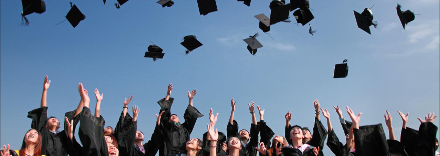 Large group of college graduates tossing their caps into the air
